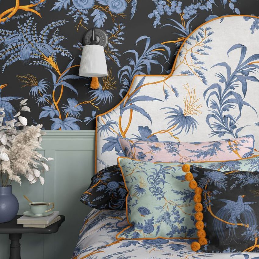 Bedroom pillows, upholstered headboard, and wallpaper mockup featuring blue and orange botanical patterns in a cozy setting.
