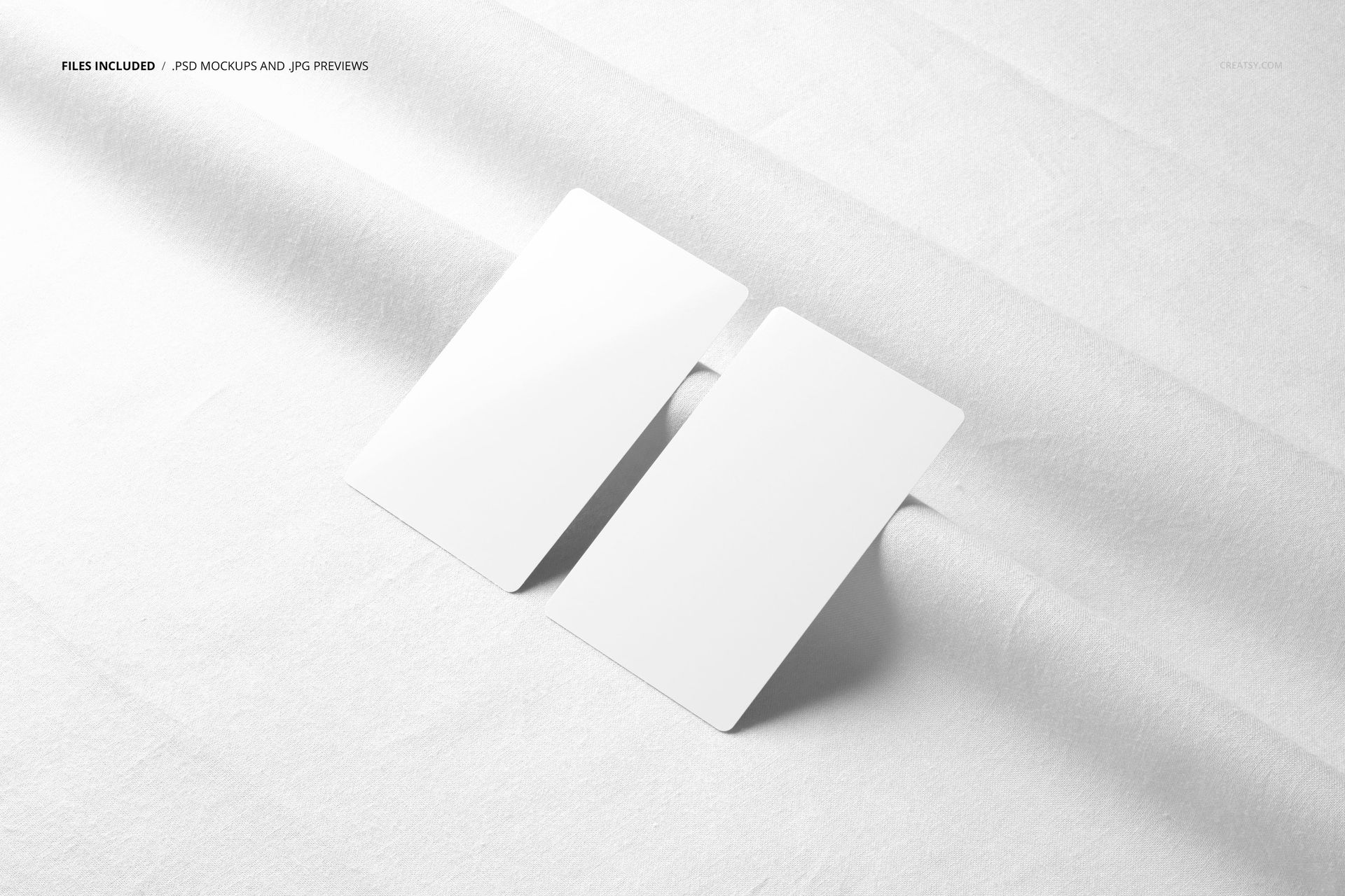Top view of two blank business cards placed on textured white cotton fabric, shown in a PSD mockup scene.