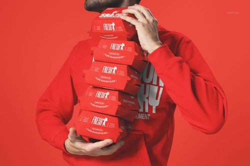 Front view of a person wearing a red sweatshirt, carrying several red burger packaging boxes, PSD mockup scene.