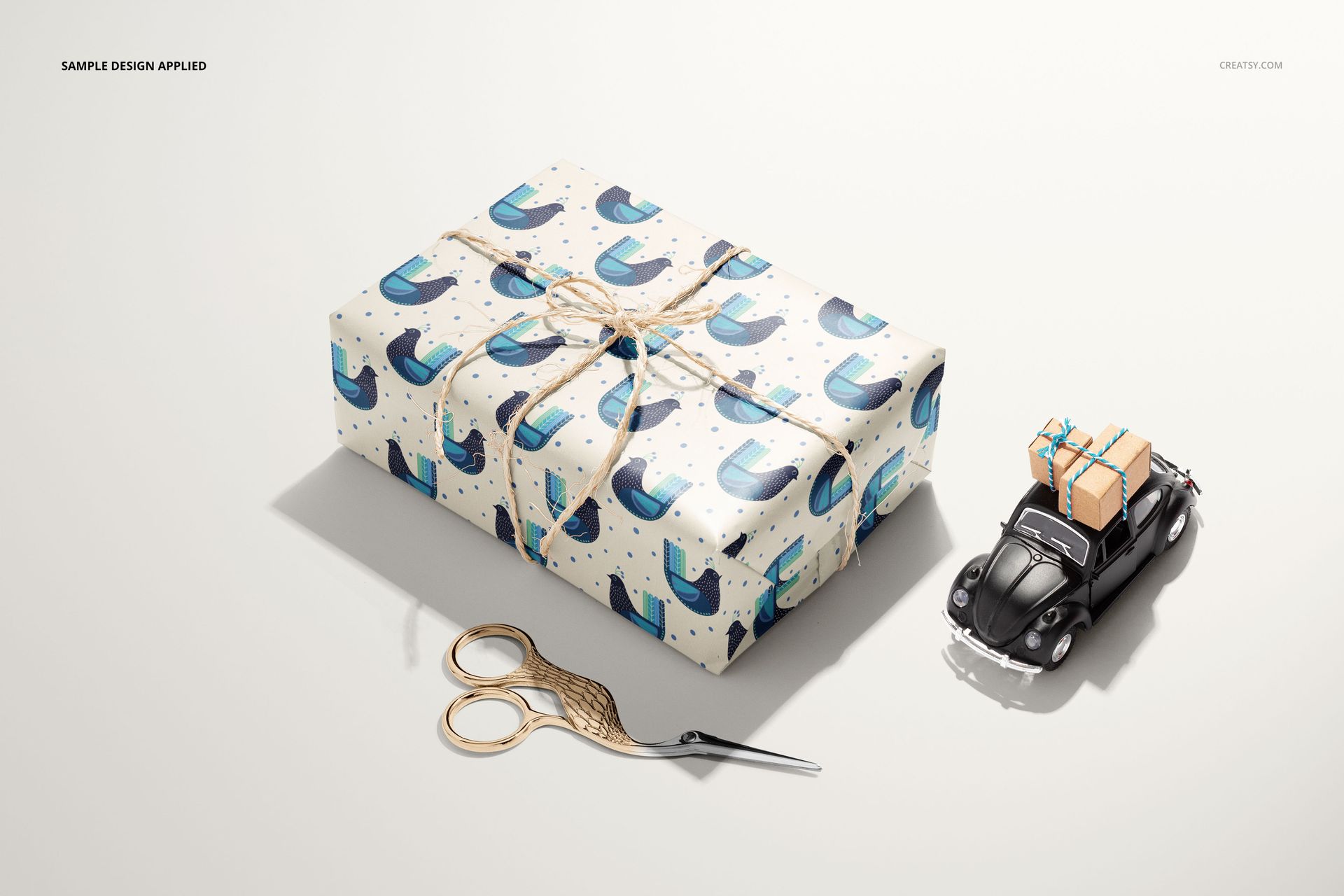 Gift wrapping paper mockup featuring a wrapped box with abstract blue pattern, twine bow, and nearby props.