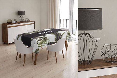 Dining table covered with a PSD mockup tablecloth featuring green palm leaves and a black runner in a bright interior.