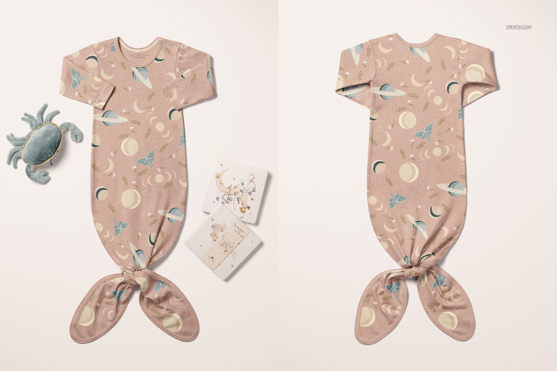 PSD mockup of a baby knotted gown featuring planets and moons, displayed flat with plush toy and cards nearby.