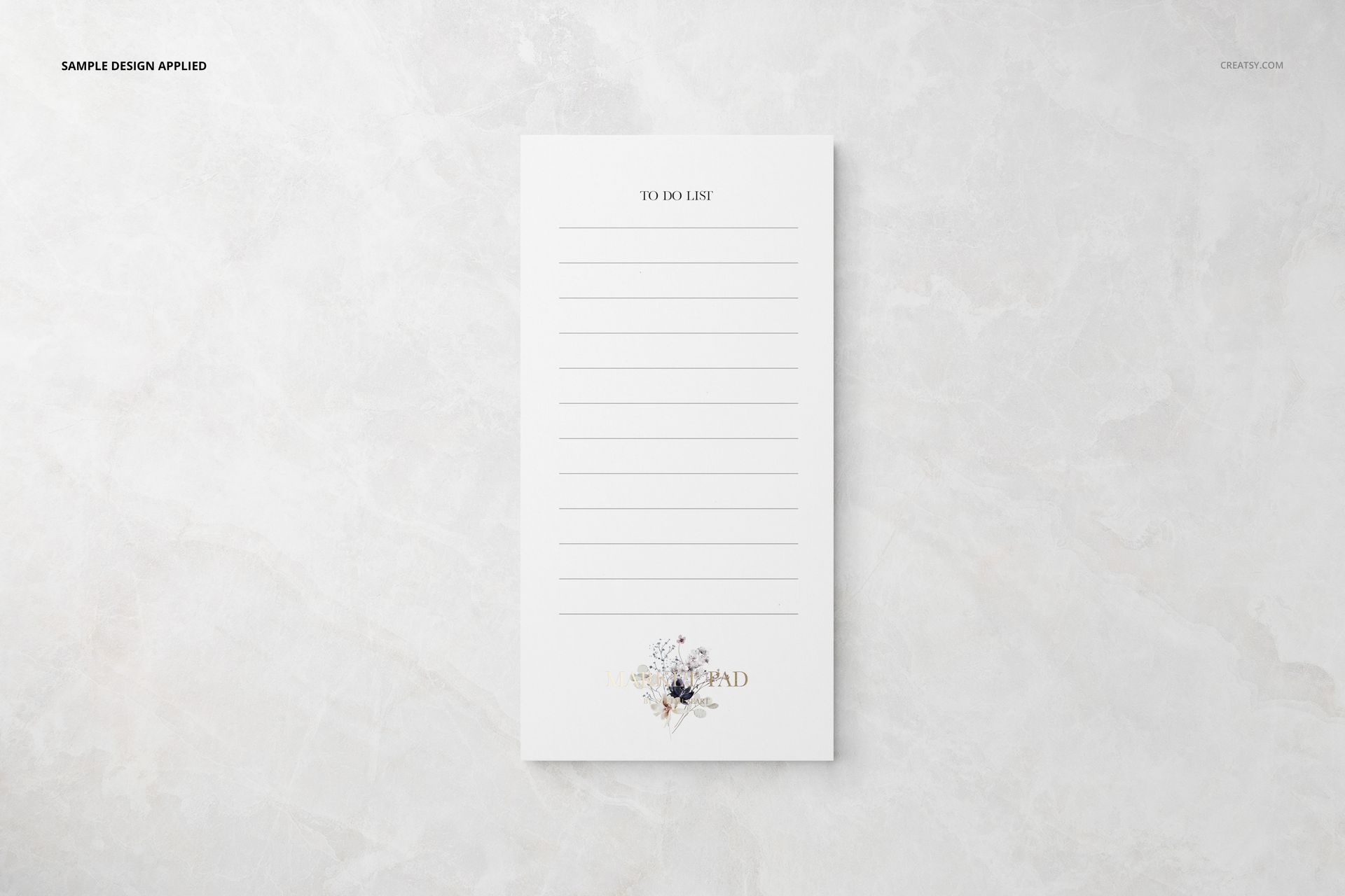 Top view of a stationery set mockup featuring a white notepad with horizontal lines and subtle floral detail.
