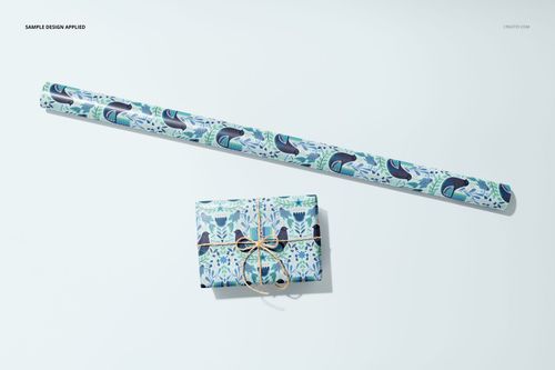 Gift wrapping paper mockup featuring a rolled sheet and a wrapped rectangular box with blue and green leaf patterns, top view.