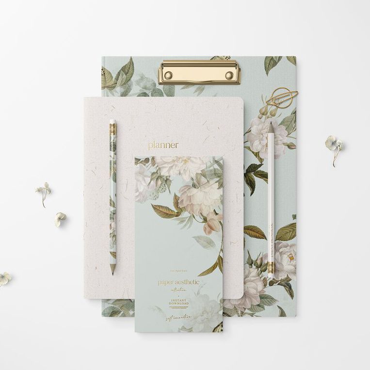 Stationery set mockup featuring a clipboard, notebook, and planner with floral designs on a white background and gold accents.