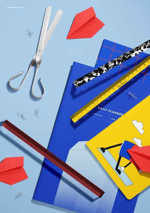 PSD mockup featuring school notebooks, rulers, scissors, and paper planes displayed on a light blue tabletop.