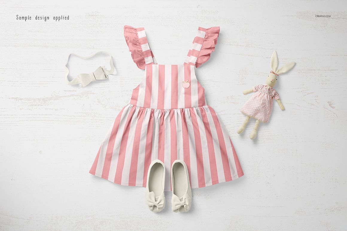 Pink and white striped baby dress mockup displayed flat on a light wooden surface with shoes and a toy bunny.