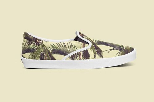 PSD mockup of a slip-on shoe with green and brown palm leaves, side profile view on a beige background.