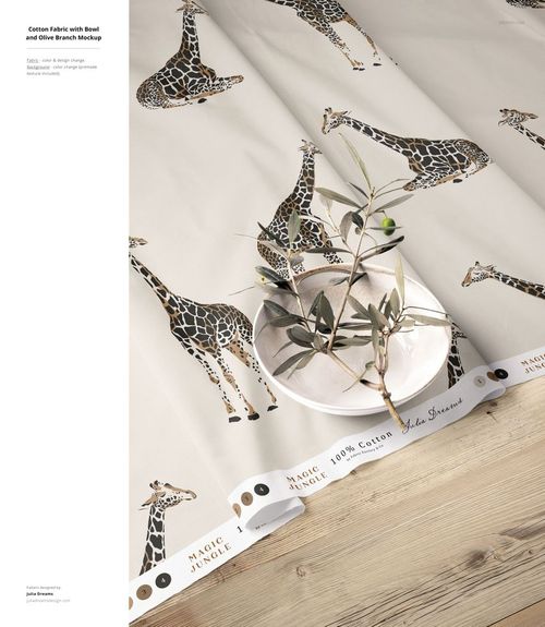 Cotton fabric mockup featuring a giraffe print pattern, displayed on a wooden surface with a bowl and olive branch.