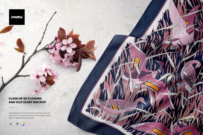 Silk scarf mockup featuring vibrant bird and plant designs, shown next to cherry blossom branches on a pale background.