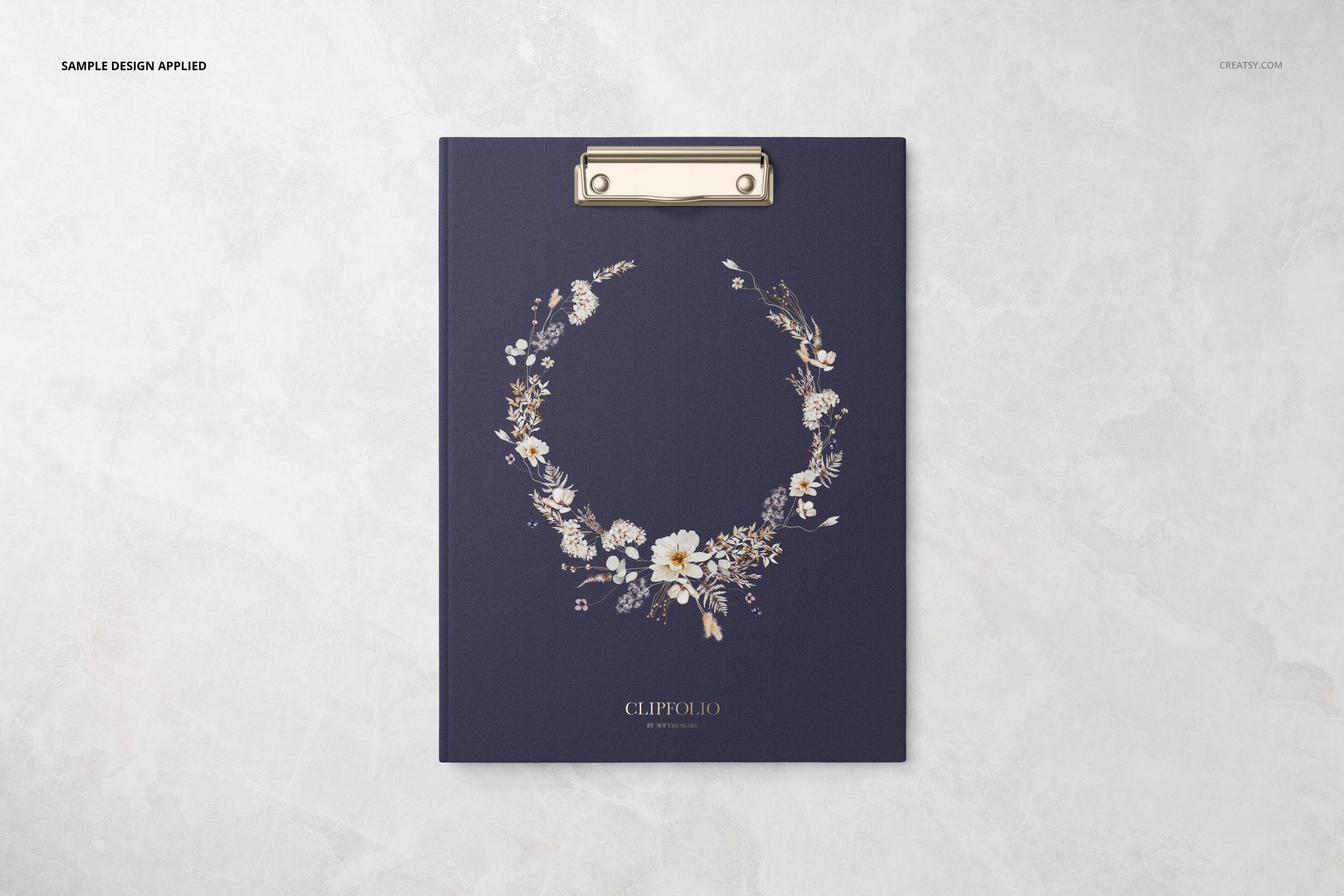 Top view of a stationery mockup showing a clipboard with a dark blue cover and decorative floral artwork.