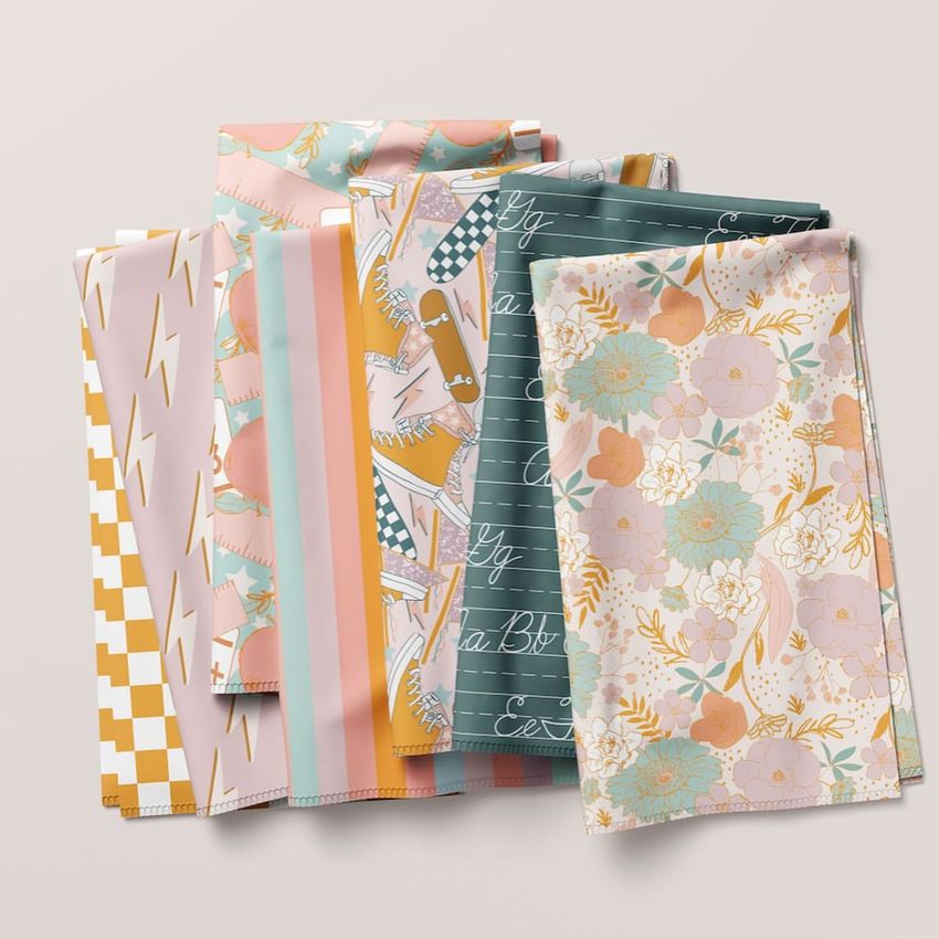 Folded fabrics mockup featuring several pieces of cloth with various pastel patterns, arranged on a light surface.