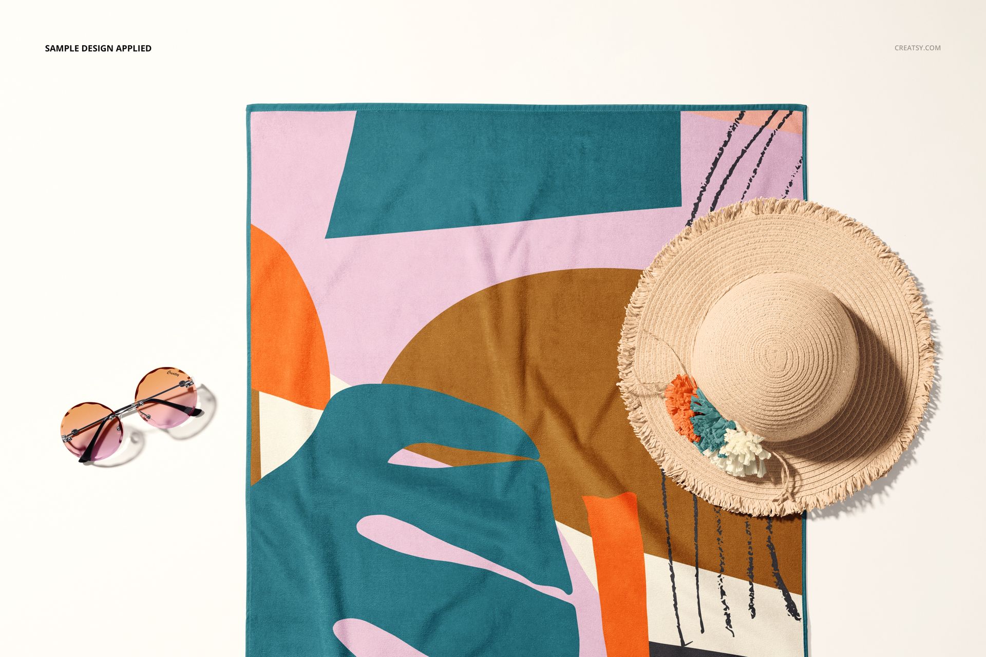 PSD mockup of a rectangular beach towel featuring bold geometric shapes, displayed flat with summer accessories nearby.