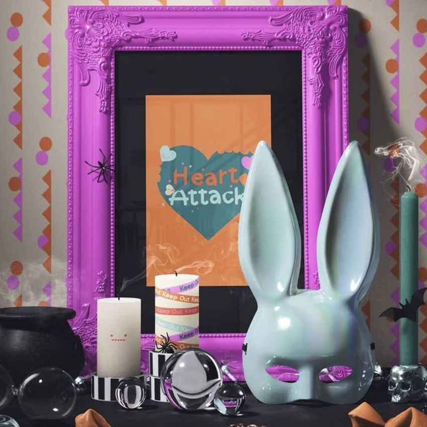 Halloween art print mockup featuring a colorful ornate purple picture frame with a heart-themed print, surrounded by candles, a bunny mask, and festive decorations.