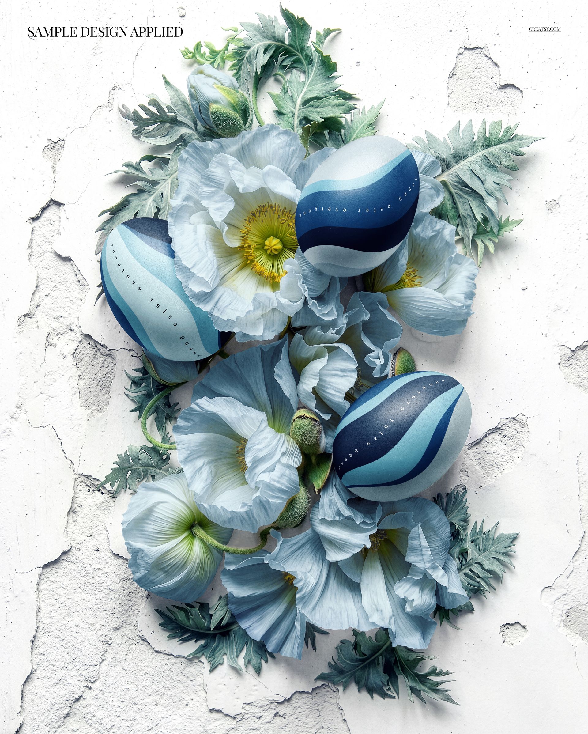PSD mockup showing blue patterned Easter eggs surrounded by delicate blue flowers and leafy stems on a rough white surface.