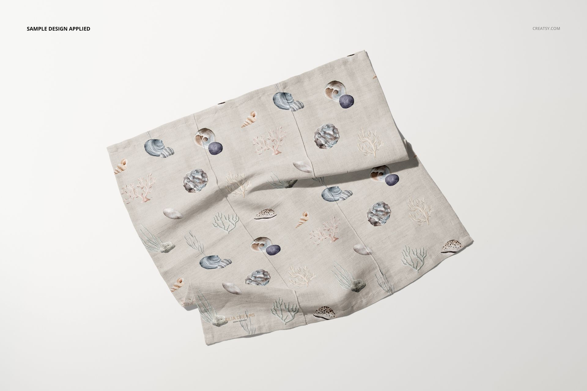 Cotton linen napkin mockup displayed at an angle on a light surface, featuring a subtle marine-themed pattern.