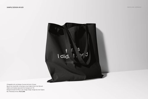 Front view of a black fabric tote bag mockup with simple white lettering, shown against a plain light background.