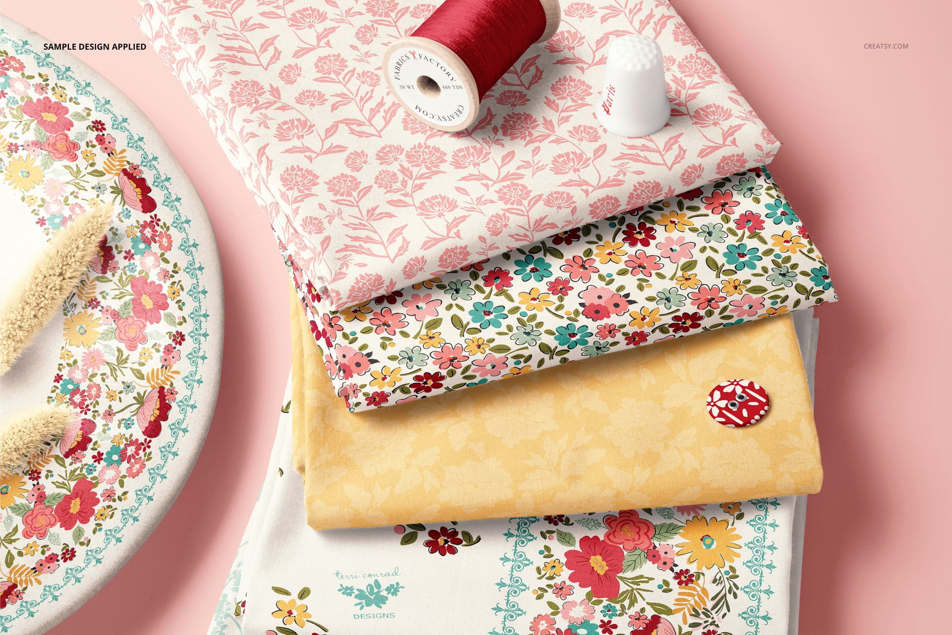 Fabric stack mockup featuring four folded textiles in floral and botanical prints, displayed with thread and thimble.