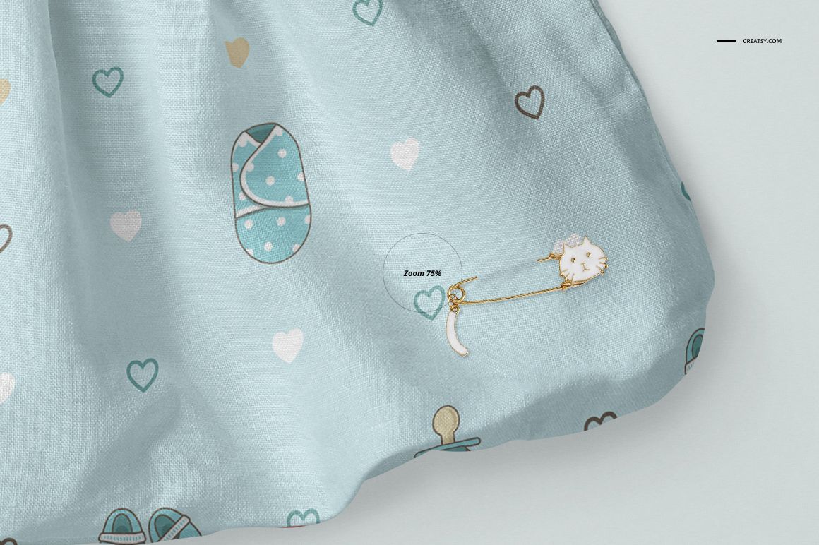 Front view close-up of a baby dress mockup with a light blue fabric, featuring heart and baby-themed patterns.