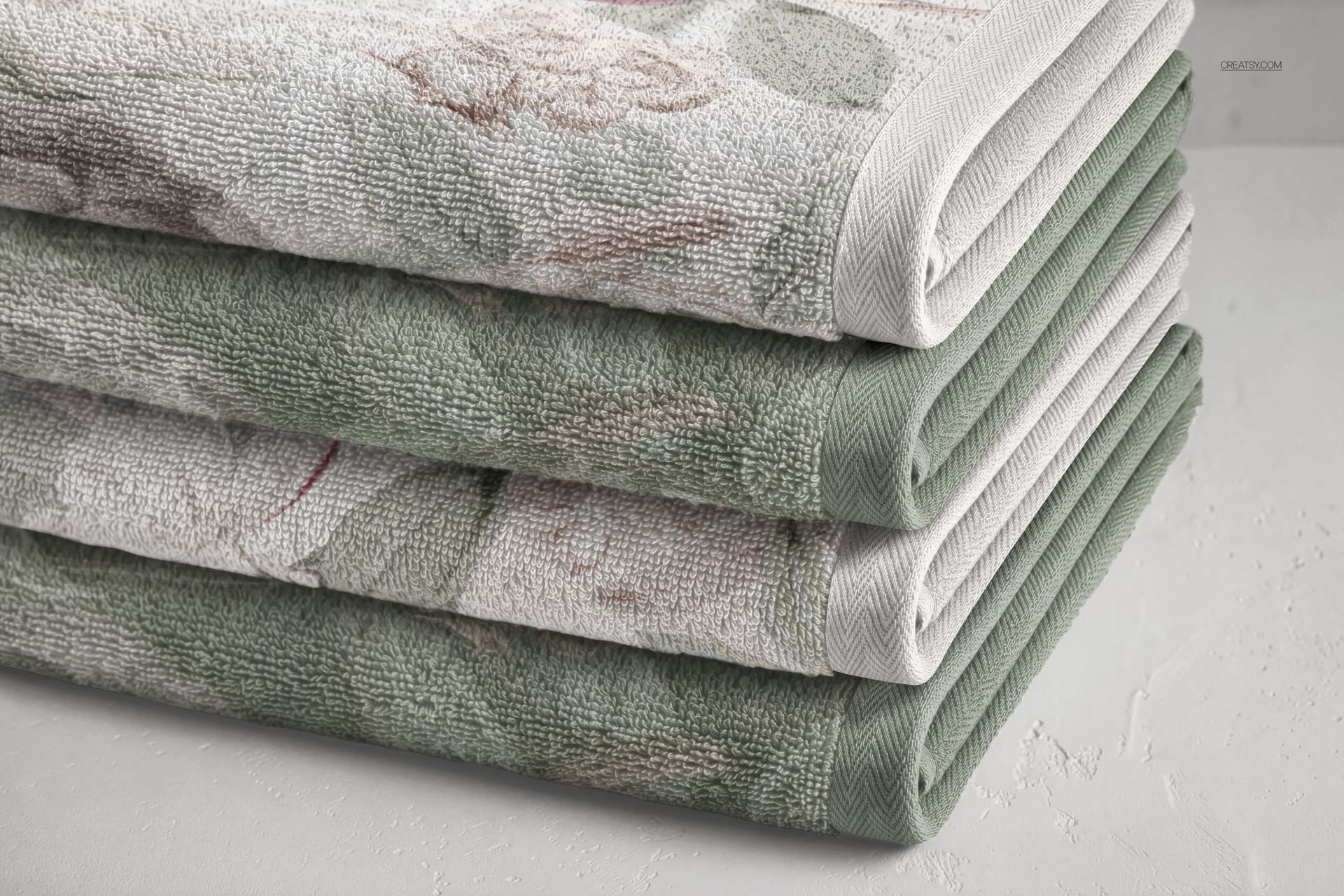 PSD mockup of bathroom towels with muted green and white colors, displaying gentle floral patterns and textured fabric.