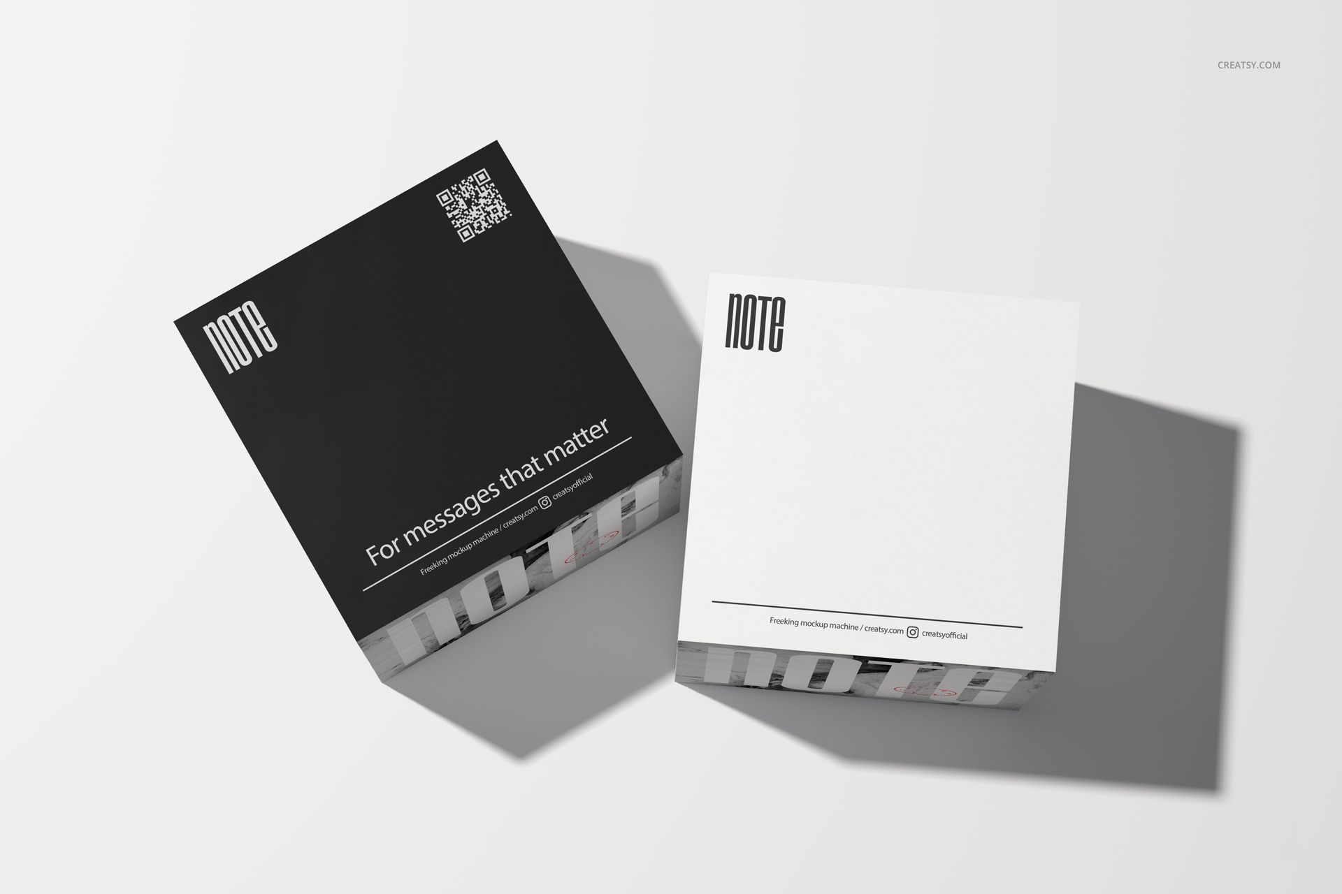 Two square note cubes with minimalist black and white covers displayed on a light surface in a stationery mockup.