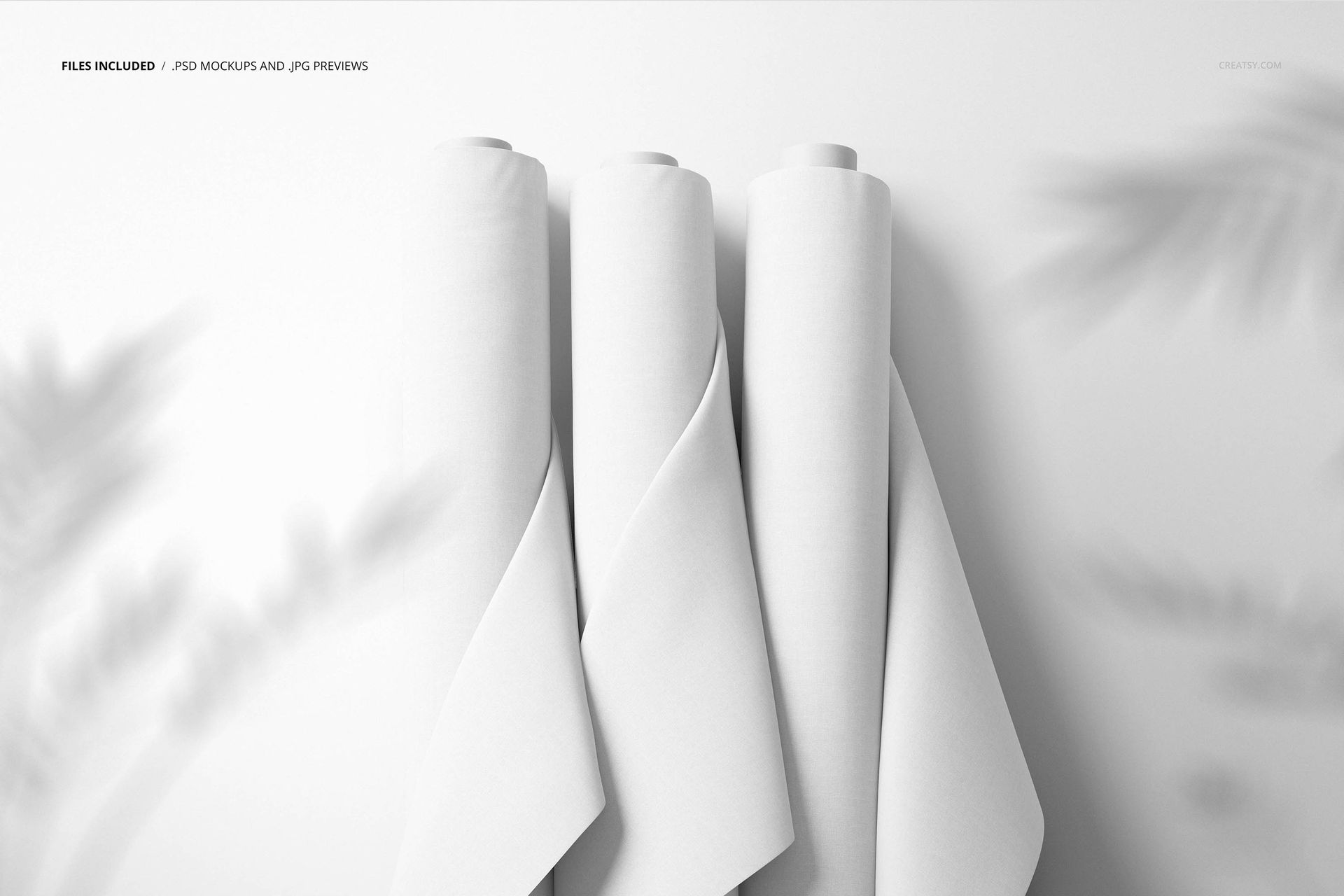 Fabric rolls mockup featuring trio of white cloth rolls, vertical orientation, on a neutral backdrop with subtle foliage shadows.