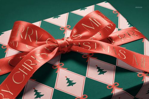 PSD mockup of a holiday gift box decorated with geometric tree design and a wide red ribbon, viewed from above.
