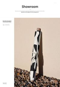 PSD mockup showing a fabric roll with bold monochrome design resting vertically outdoors on rocky ground.