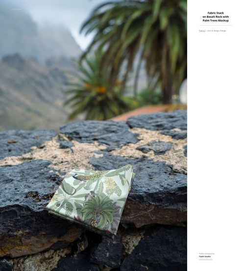 Fabric mockup displaying botanical patterns, set on a rocky ledge with palm trees and misty mountains behind.