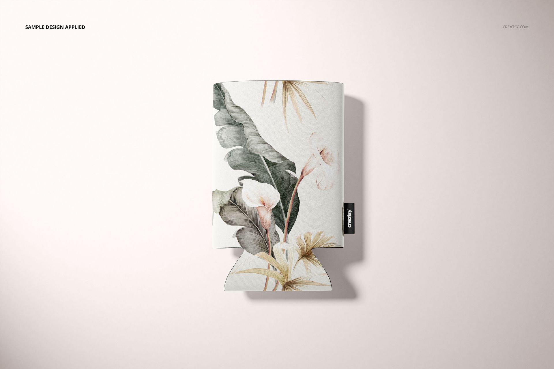 PSD mockup of a neoprene can cooler featuring botanical leaves and flowers, displayed flat against a pale surface.