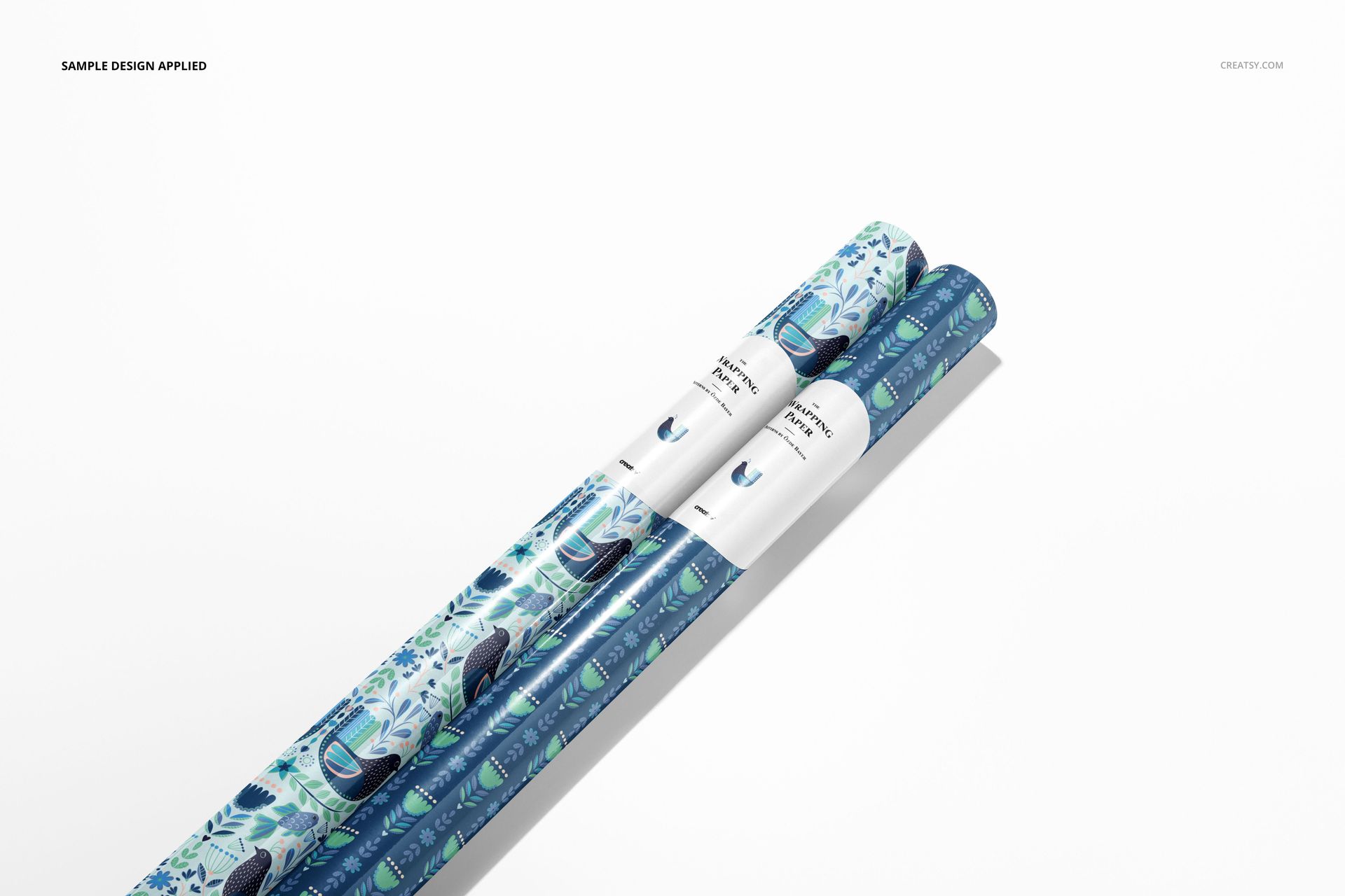 Gift wrapping paper mockup with two patterned rolls in blue and green tones, positioned diagonally on a white backdrop.