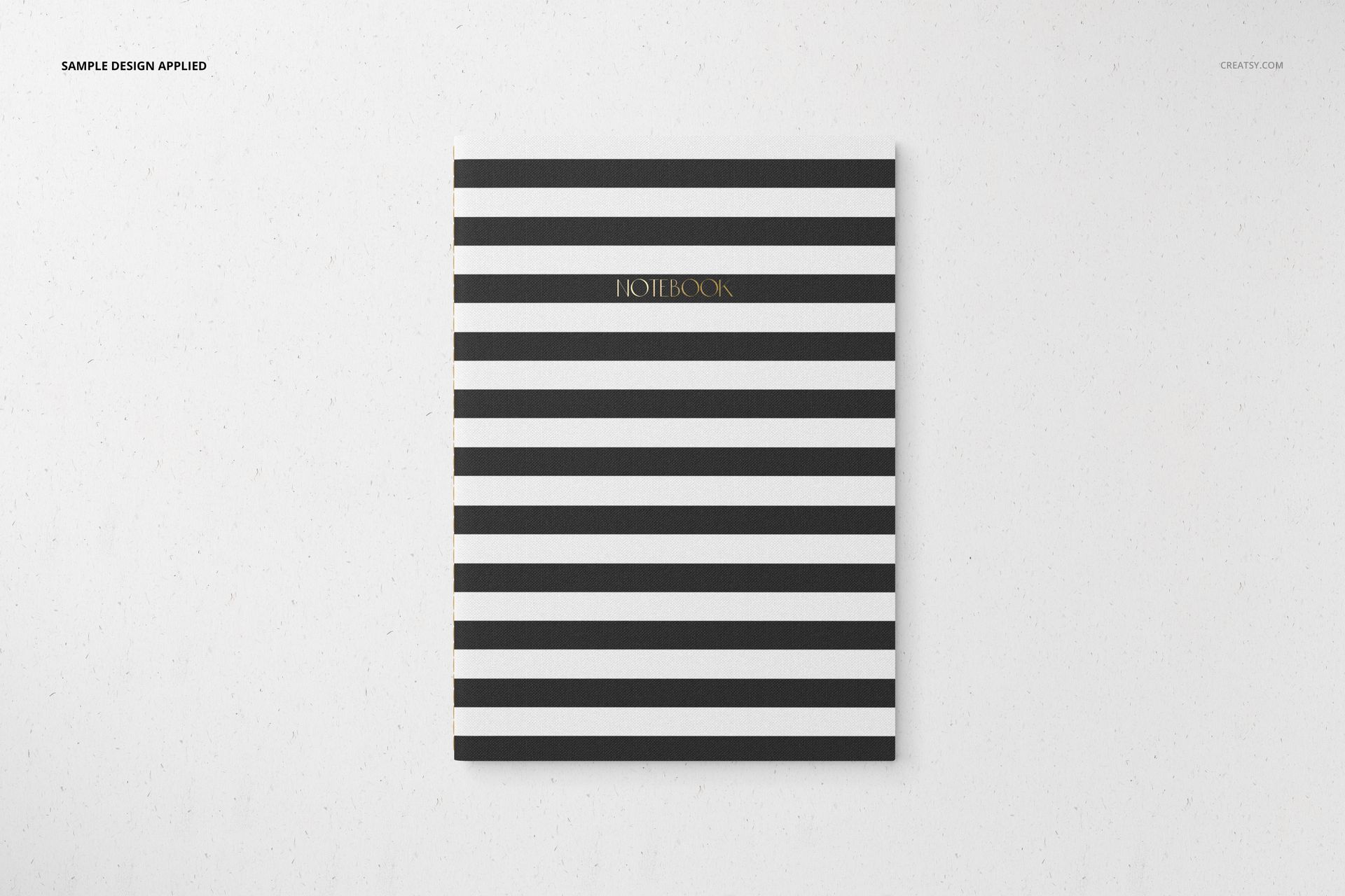 Stationery set mockup featuring a striped notebook with black and white lines and gold lettering on the cover.