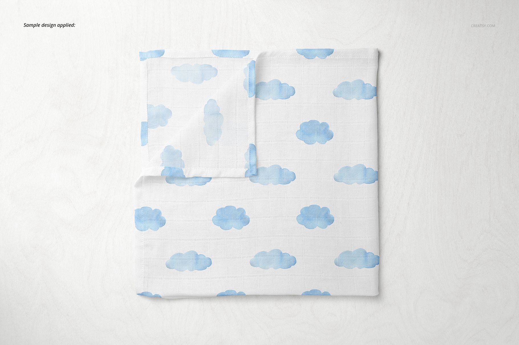 Baby muslin square nappy mockup featuring a white cloth with blue cloud pattern, shown from a top view on a light surface.