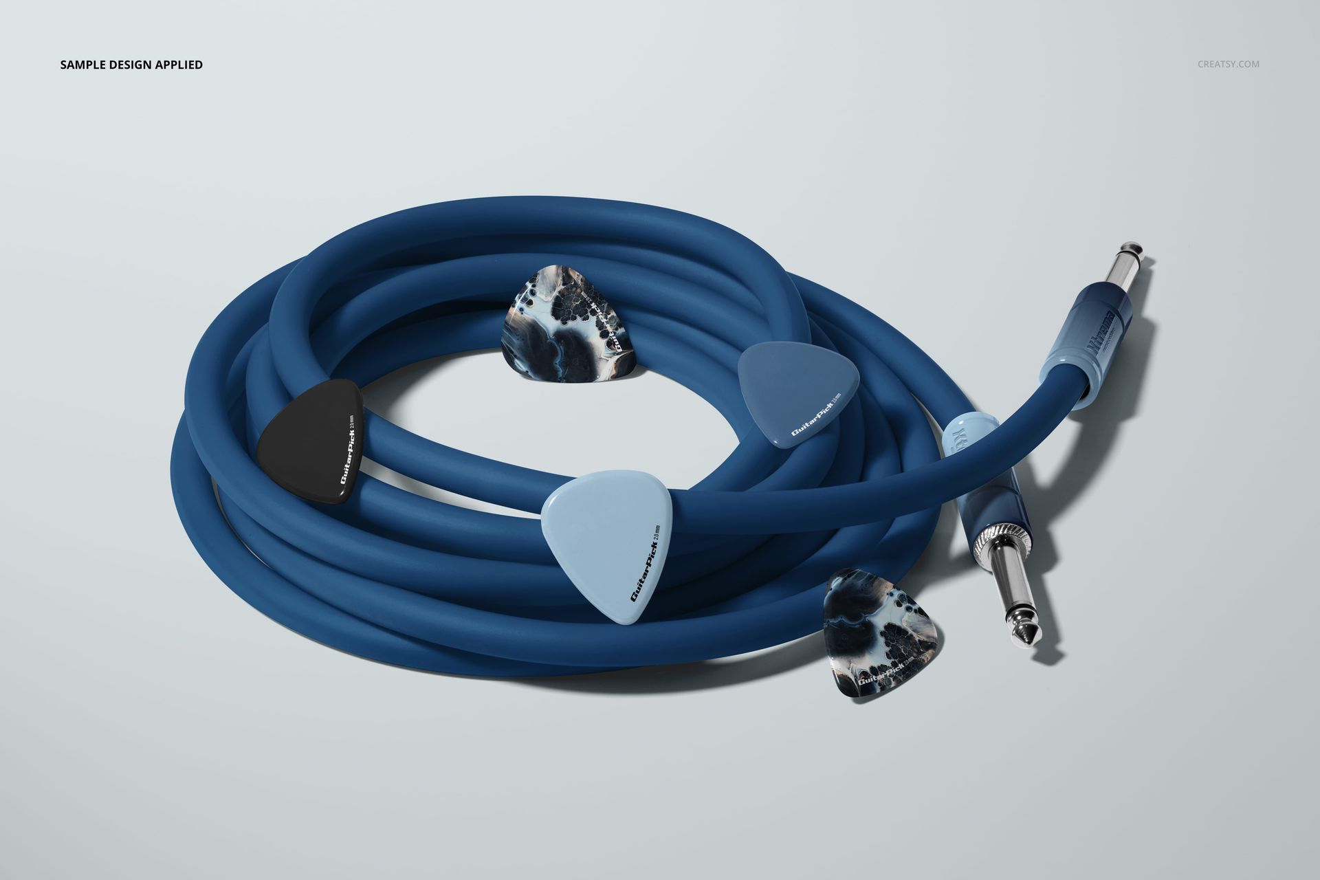 Close-up of a blue guitar cable mockup with four guitar picks in various colors and patterns arranged around it.