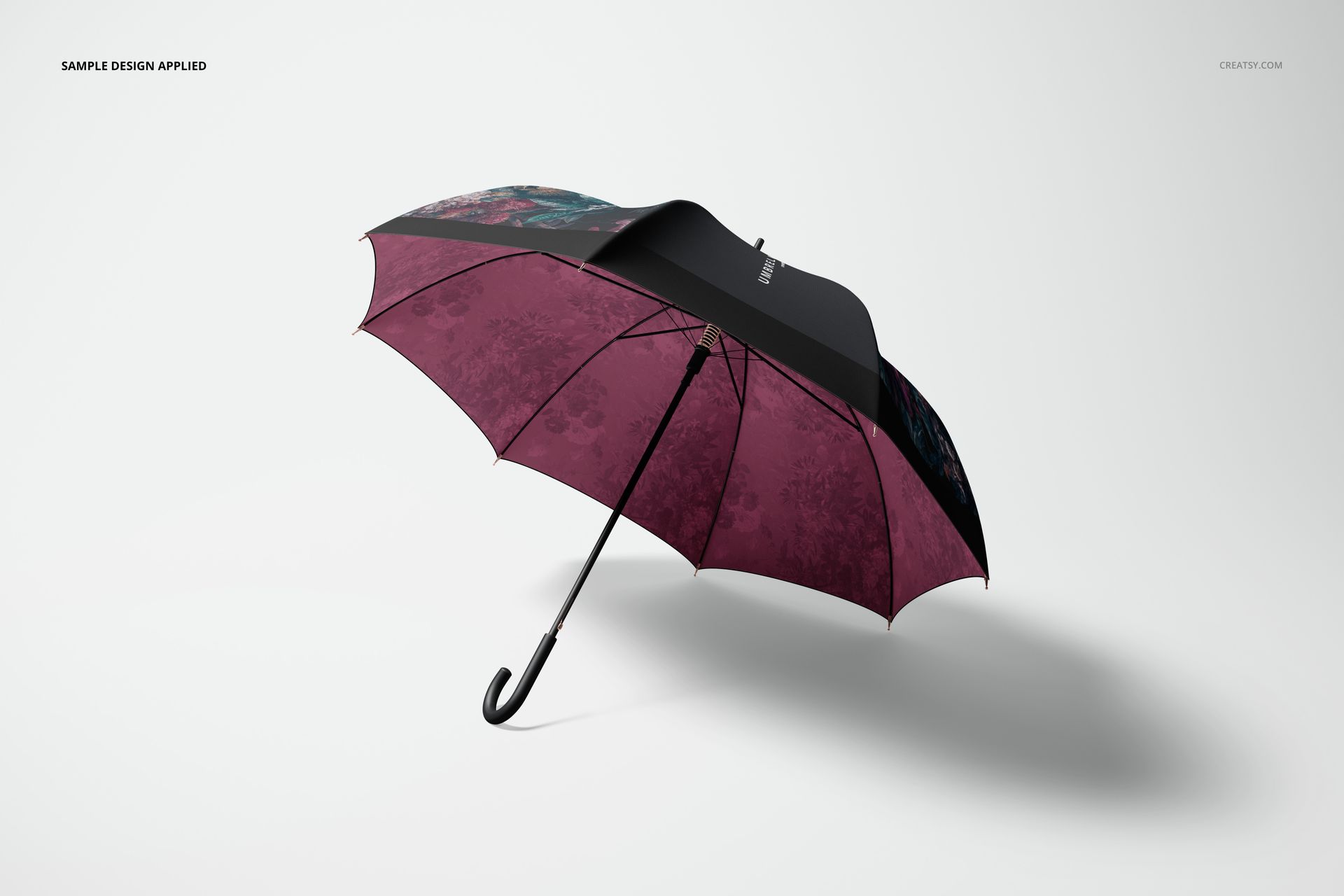 Umbrella mockup showing maroon floral patterned panels and a black canopy, presented at an angle on a plain background.