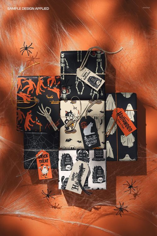 PSD mockup of Halloween gift wrap boxes with ghost, bat, and spider motifs, displayed with decorative tags and twine.