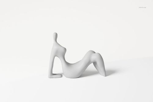 Minimalist abstract sculpture with a smooth matte surface, featuring a reclining human-like form on a white background.