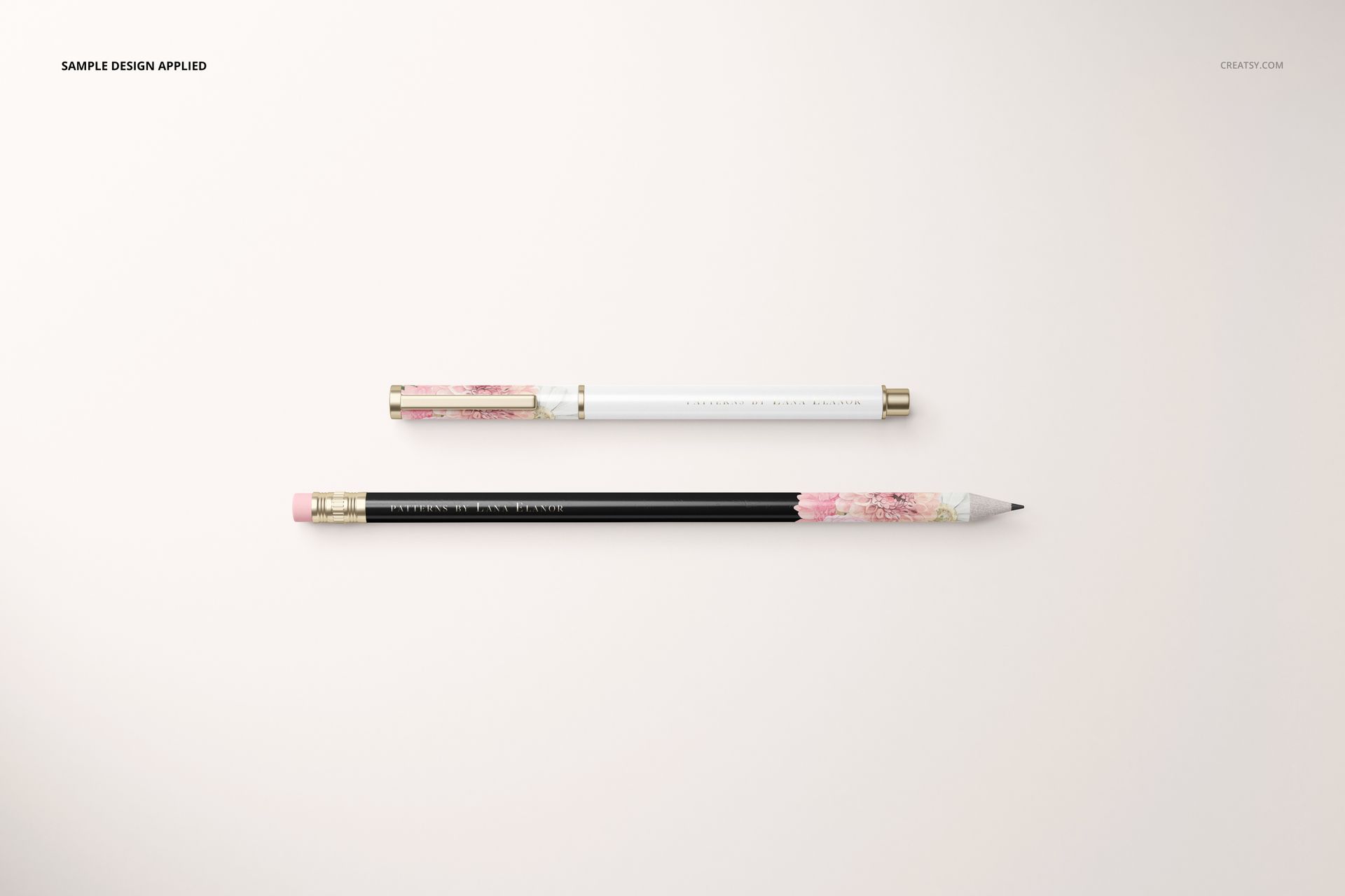 Stationery set mockup featuring a pen and pencil with gold accents and floral patterns on a light background, top view.