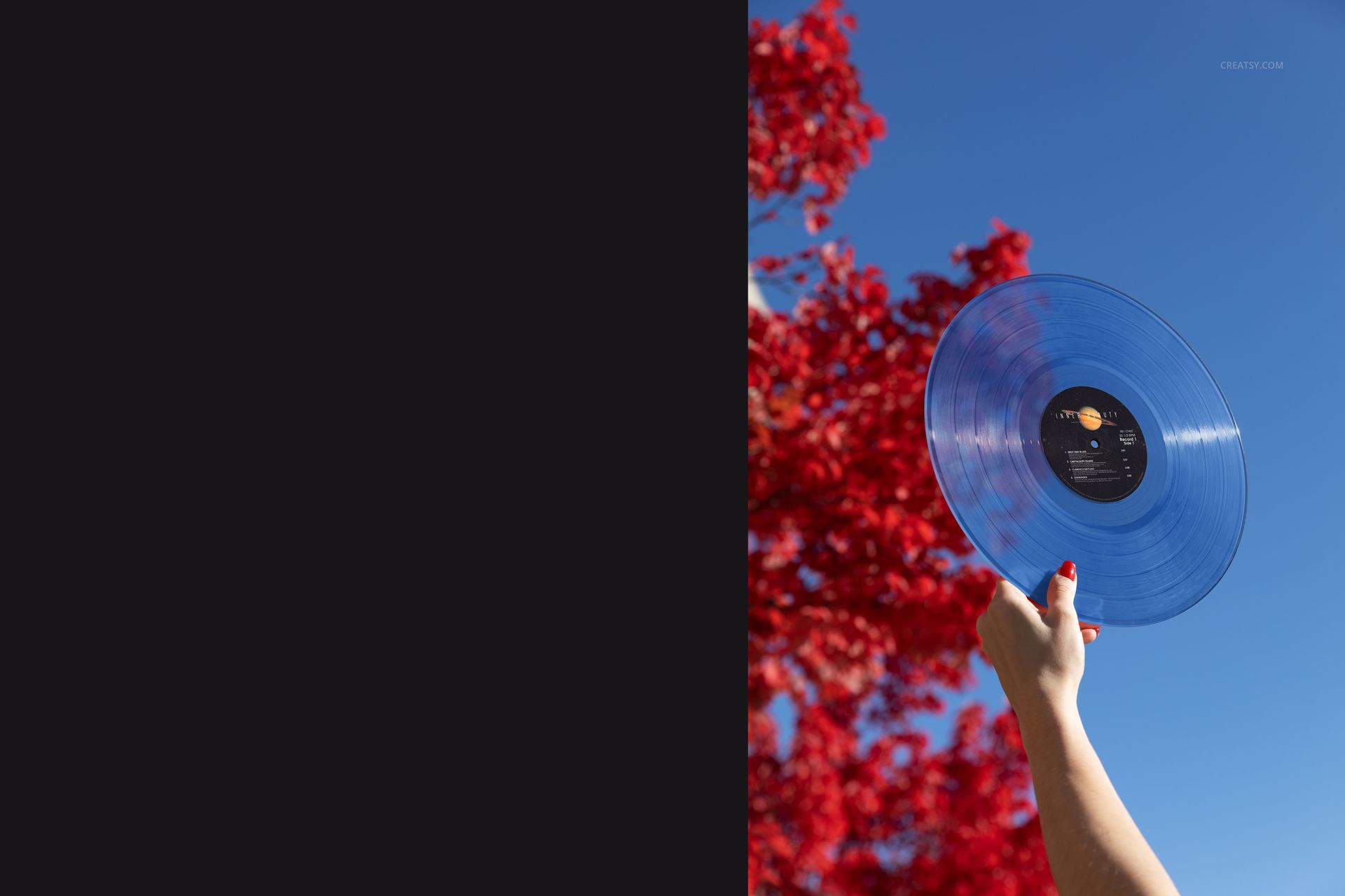 Translucent colored vinyl record mockup shown outdoors, held up by a hand with red nails, tree in background.