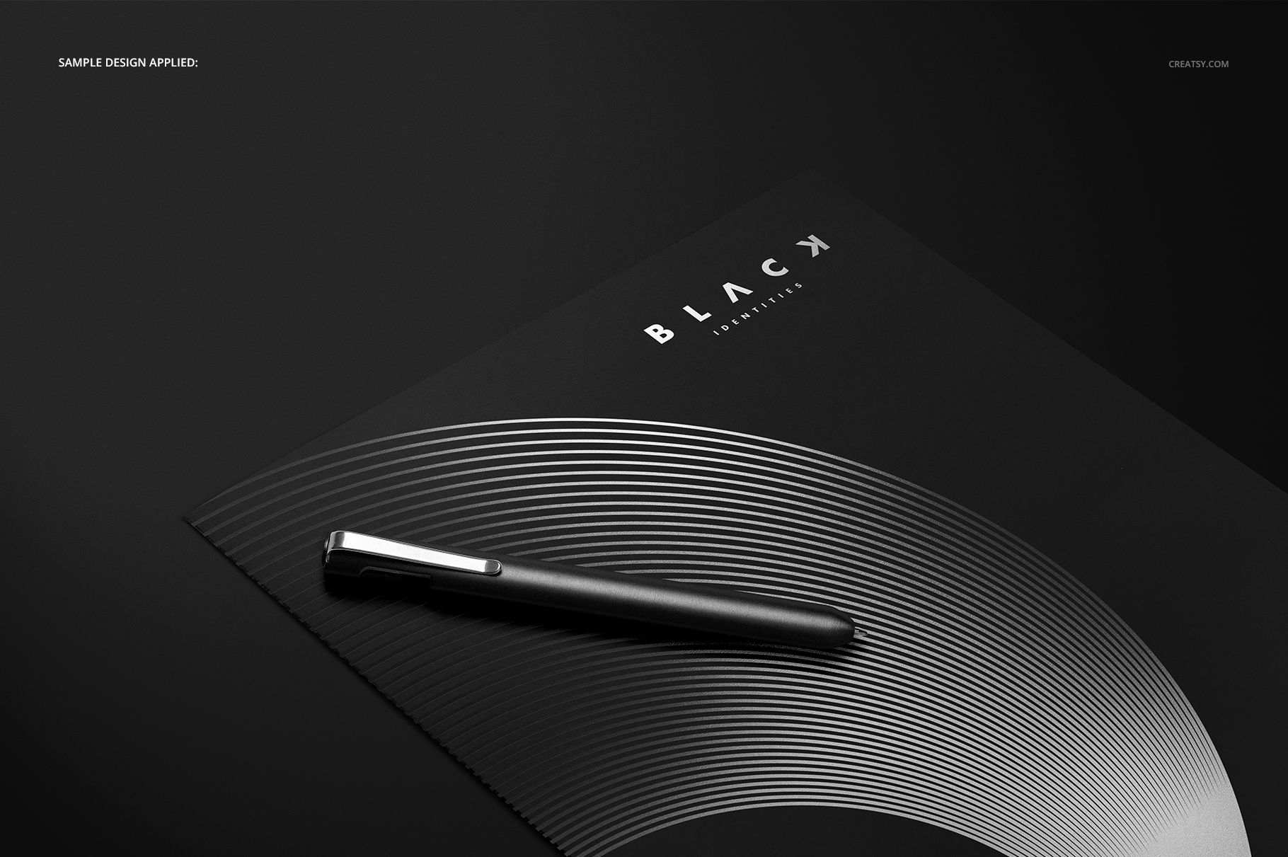 Black stationery folder mockup featuring a silver concentric circle design and a pen on a minimalist dark surface.