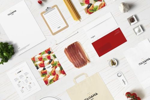 Italian restaurant stationery mockup featuring menus, envelopes, and branded paper items arranged on a white wooden surface.