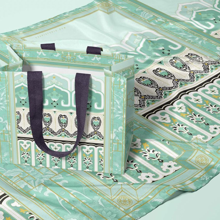 Silk scarf mockup with an ornate mint green and gold pattern, displayed beneath a matching paper bag with dark handles.