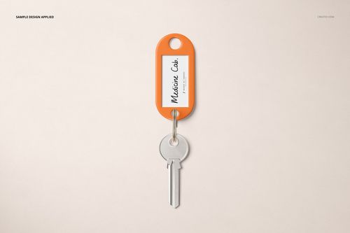 Key tag mockup with an orange border and white insert, holding a silver key, shown on a plain light surface.