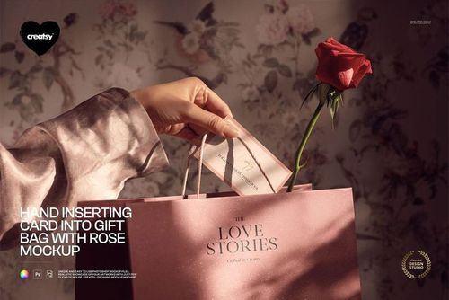 Front perspective of a pink gift bag mockup featuring a hand, a card, and a red rose, with muted floral decor.