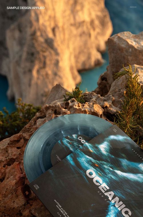 Translucent vinyl record mockup and square album cover with blue ocean design, set on rocks above a blue sea.