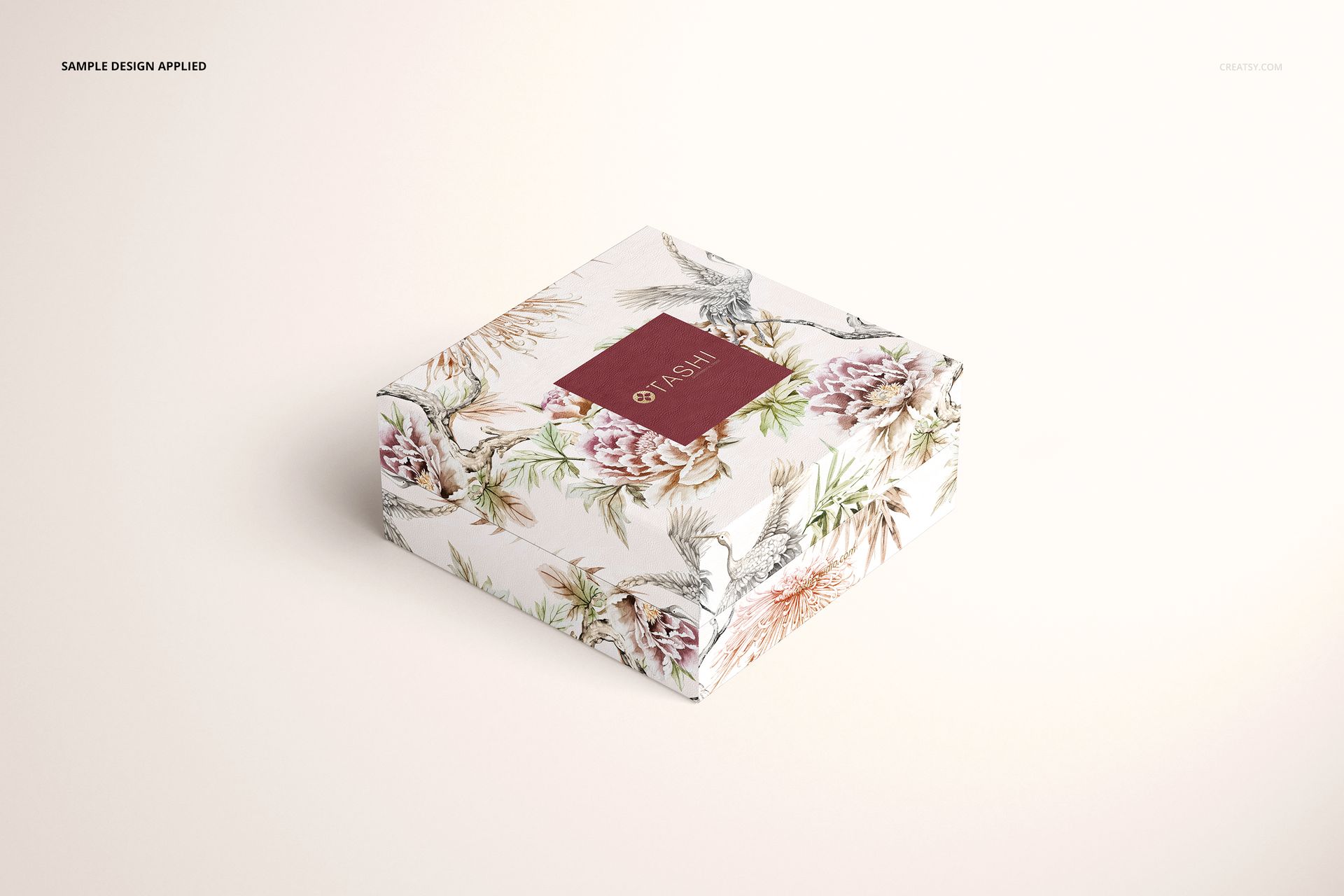 Square jewelry box with floral and bird pattern, viewed from a front angle on a light background, mockup style.