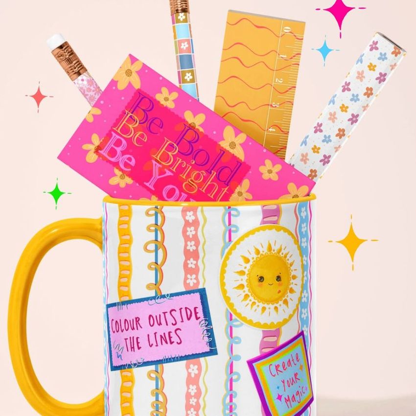 Mug mockup with a colorful, hand-drawn design holds pencils, a ruler, and a bright pink card with bold text, set against a light background.