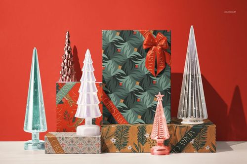 Christmas-themed PSD mockup showing a gift box with festive ribbon and leaf design, placed among holiday tree ornaments.