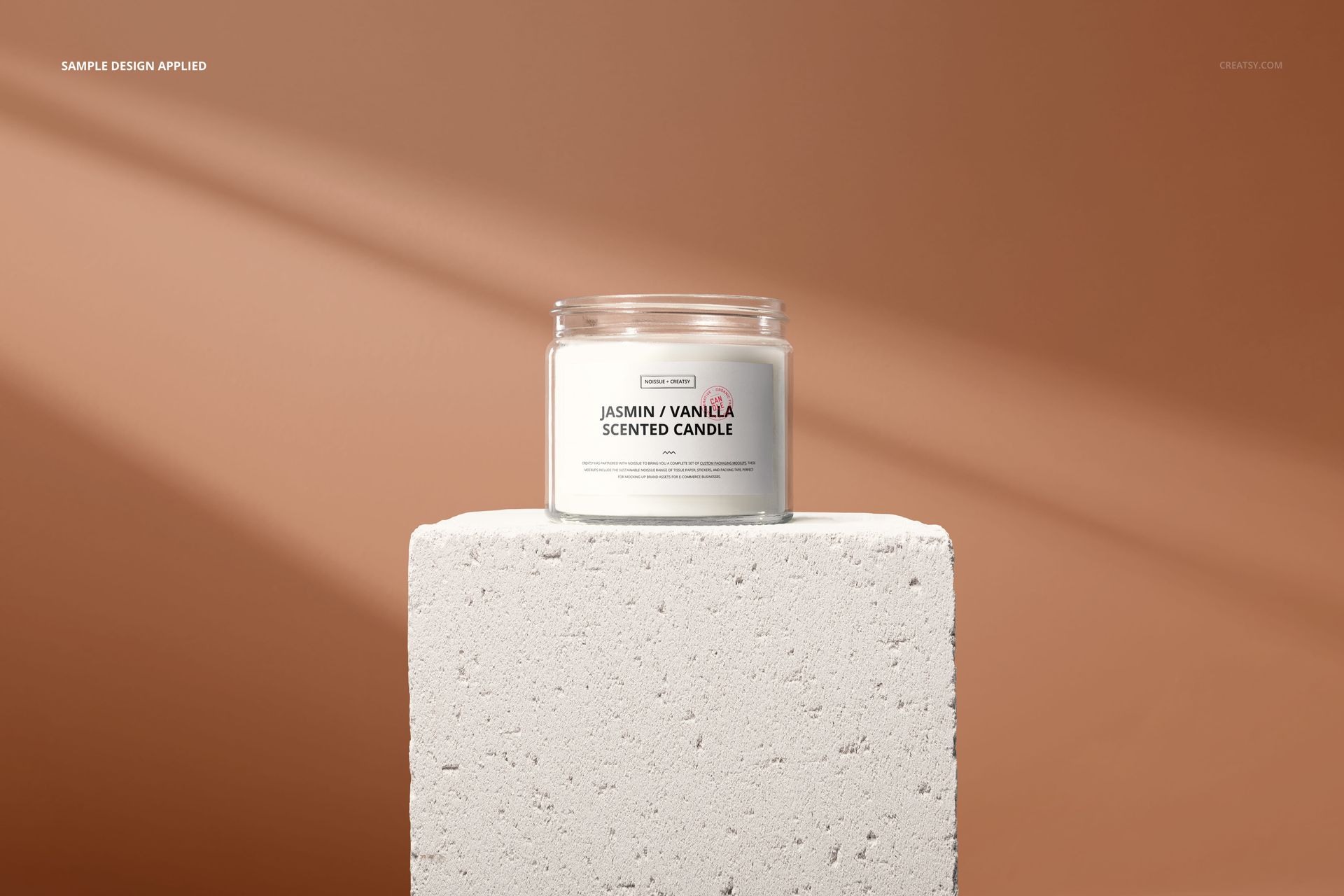 Minimalist jar candle mockup featuring a clear glass container with a white label, set on a stone block, front perspective.