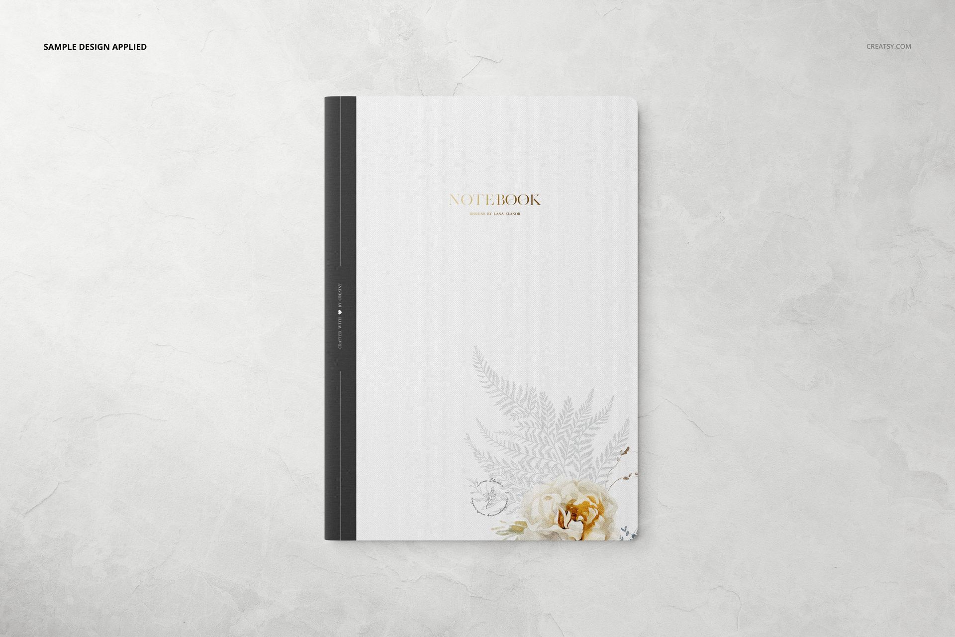 Top view of a stationery set mockup featuring a white notebook with botanical artwork and a dark vertical spine.
